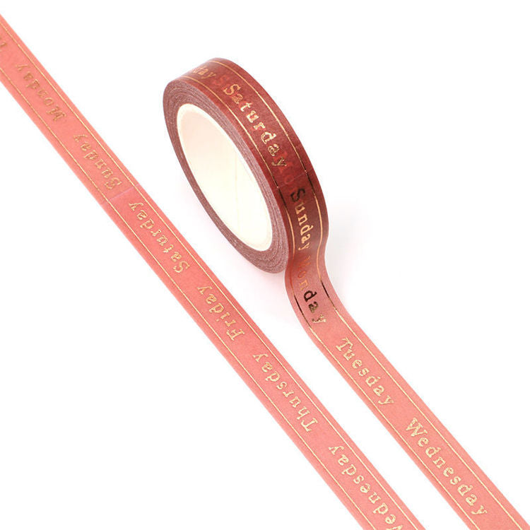 Image shows a pink washi tape with printed days of the week in gold foil