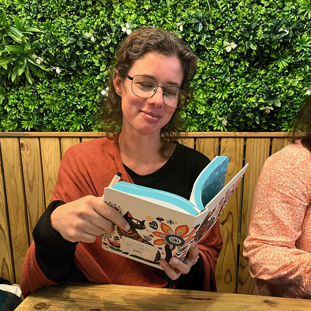 Image shows a woman sitting with a MOM/WOW diary in hand