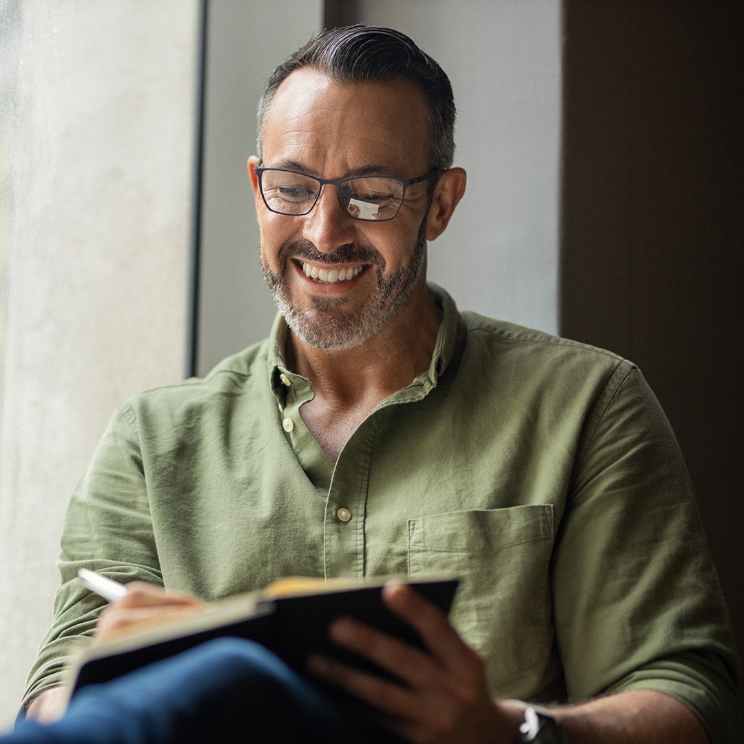 Image shows a man writing in a journal