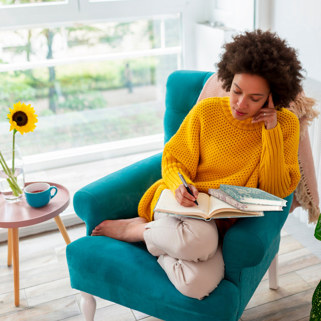 Image shows a woman writing in a Premium hardcover journal