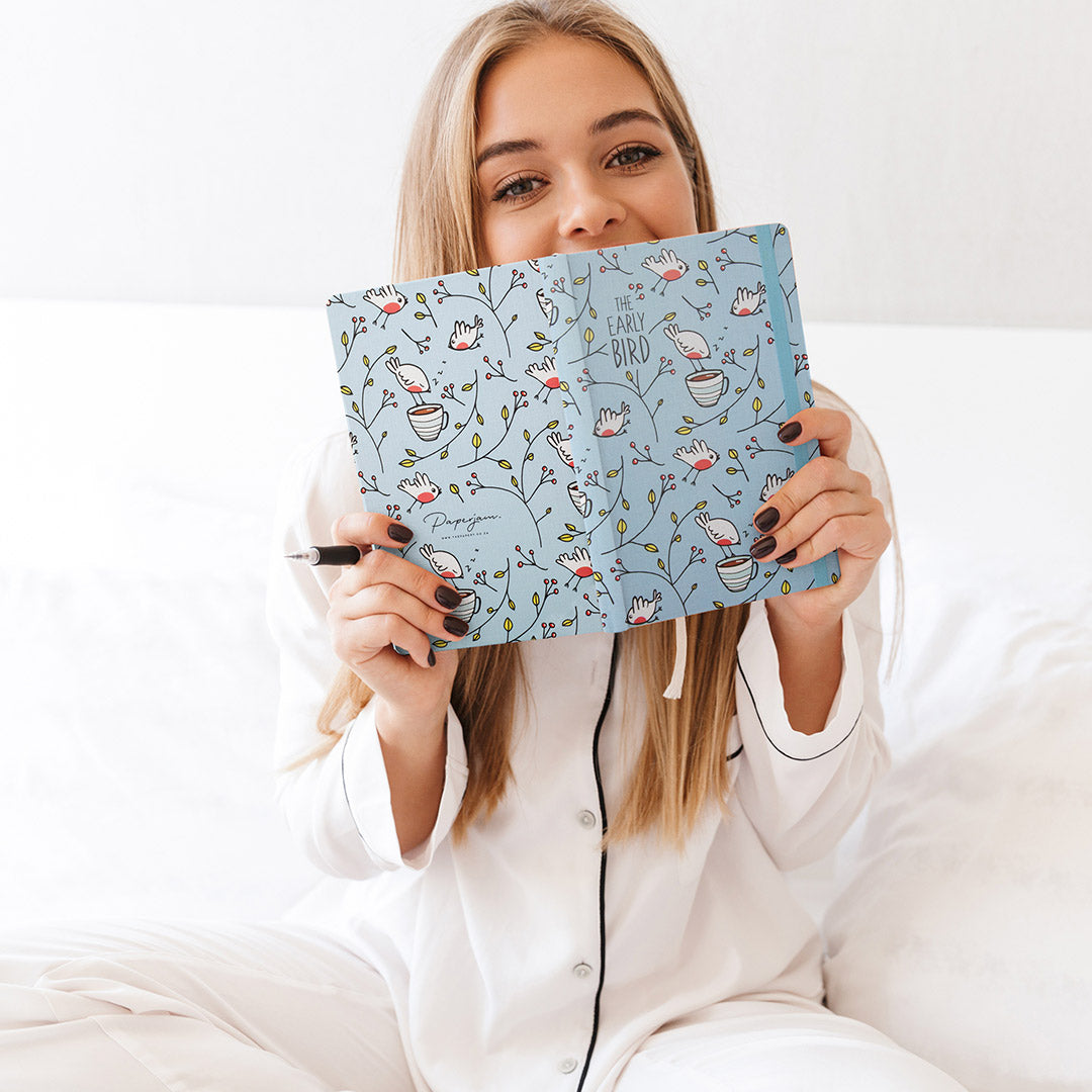 Image shows a woman holding up a Retro hardcover journal in hand