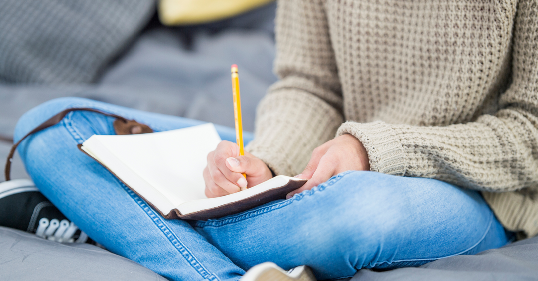 Woman writing in a journal doing therapeutic journalling