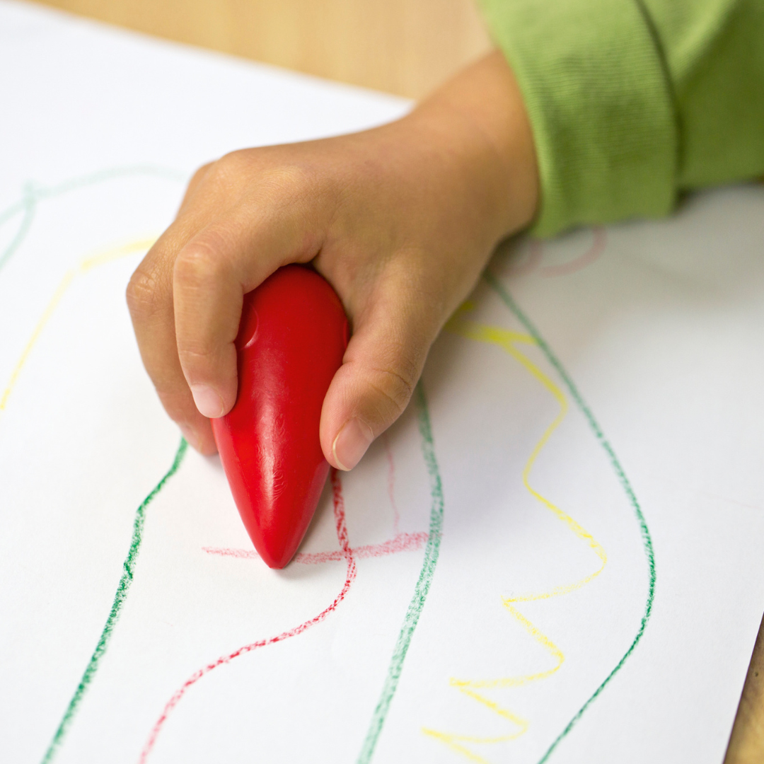Image shows a child writing with Faber-Castell grasp crayons 