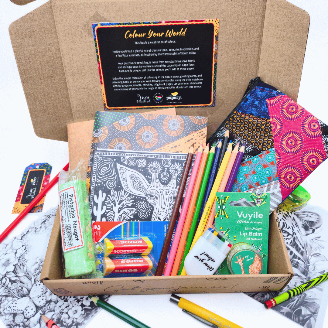 Coloring supplies including notebooks, pencils, and a lip balm in an open cardboard box.
