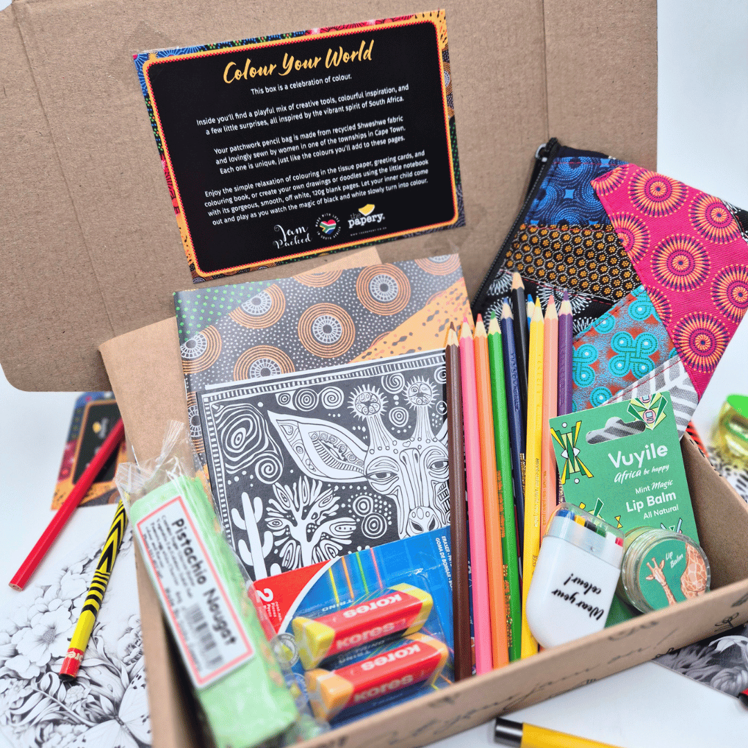 Box of stationery items including coloring books, pencils, and lip balm with a card reading 'Colour Your World' on a white surface.