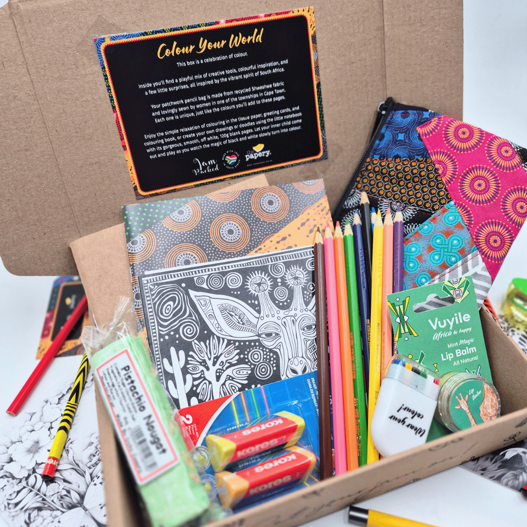 Box of stationery items including notebooks, pencils, and lip balm with a 'Colour Your World' card.