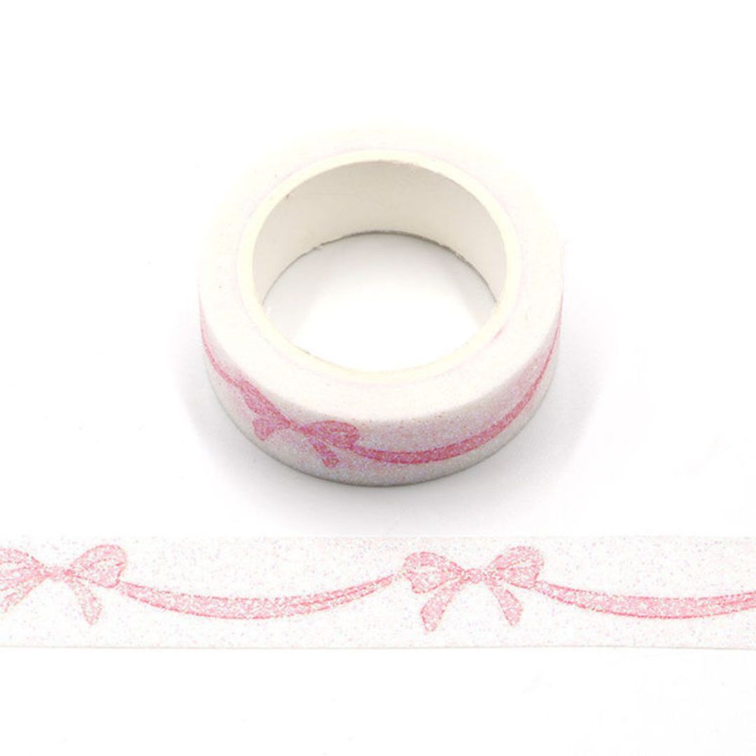 Roll of pink decorative  washi tape with a bow design on a white background