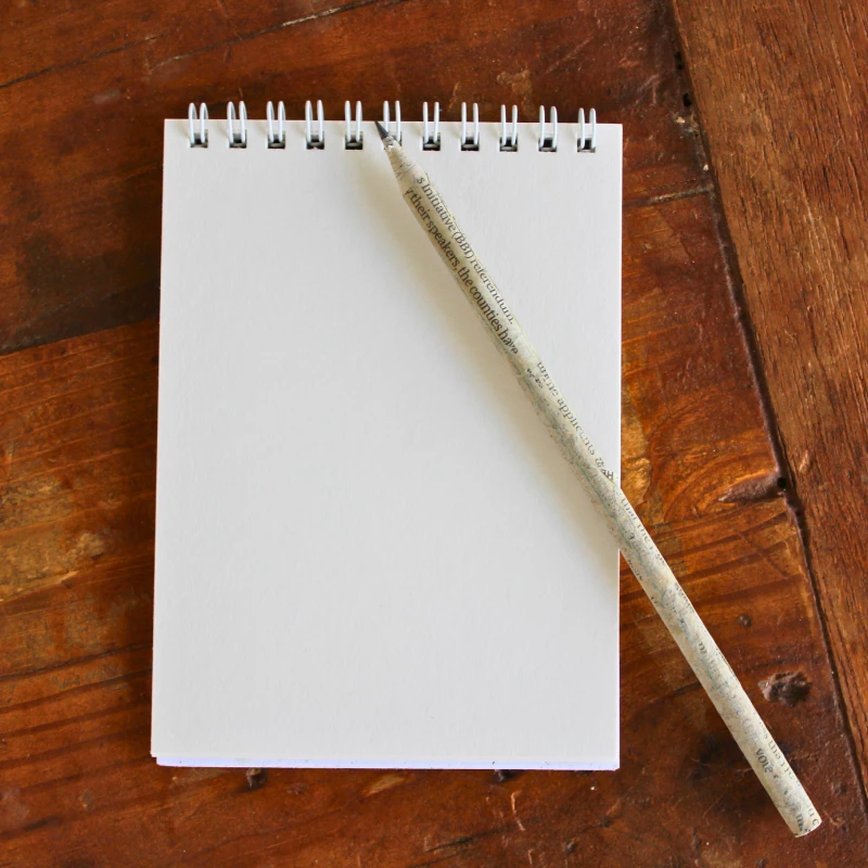 Image shows a recycled writing pencil with notebook